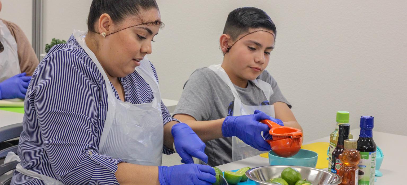 Mom and son squeezing limes for juice in a classroom