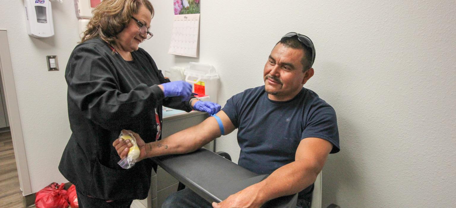 Female doctor drawing the blood of a male patient