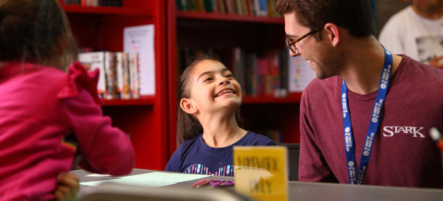 young girl looking up at teenage boy while working on homework