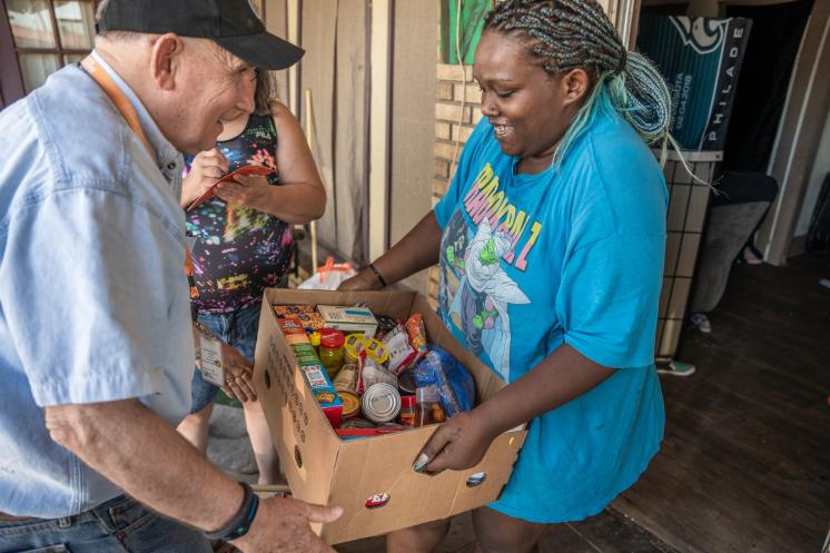 Older man handing a woman a box of food