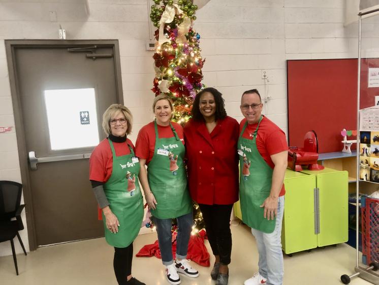 Four people posing in front of a Christmas tree