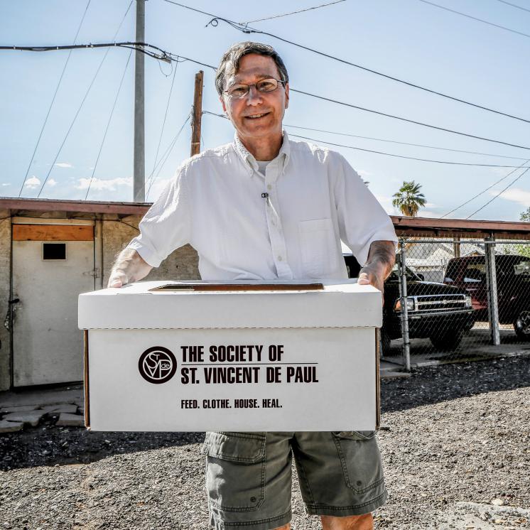 A volunteer holds a SVdP foodbox.