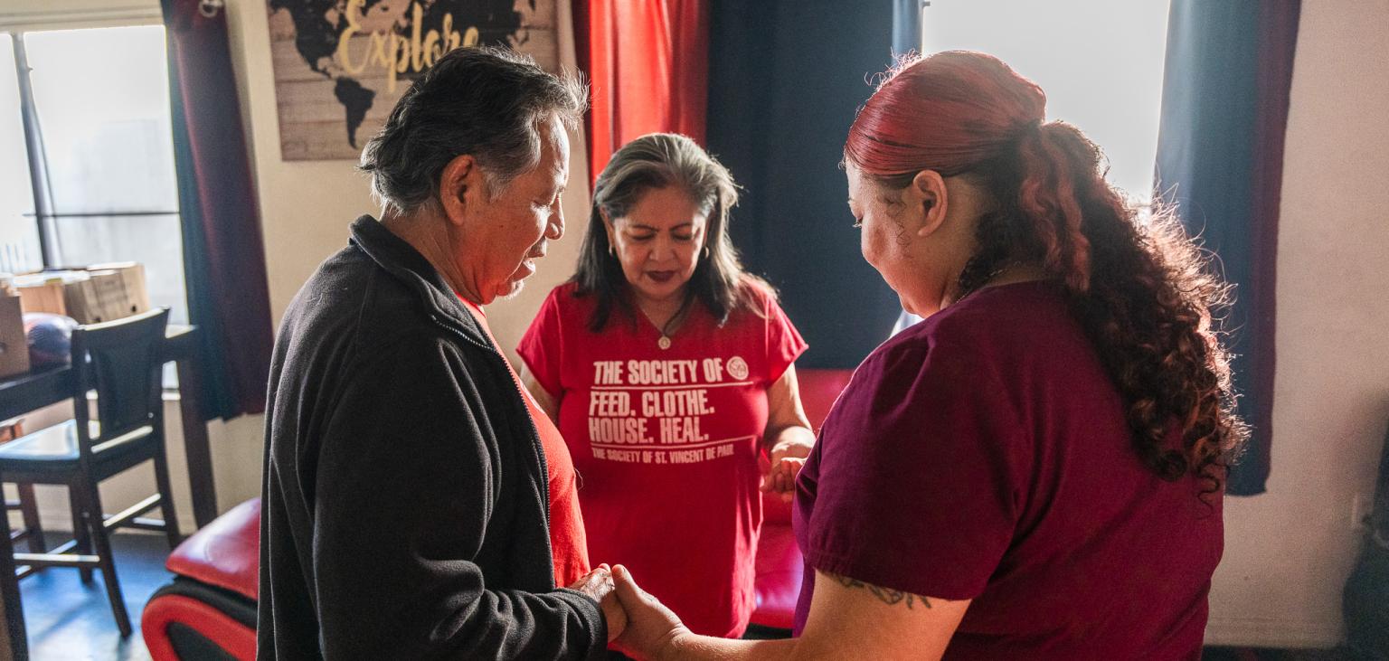 Vincentians pray with a mother during a home visit.