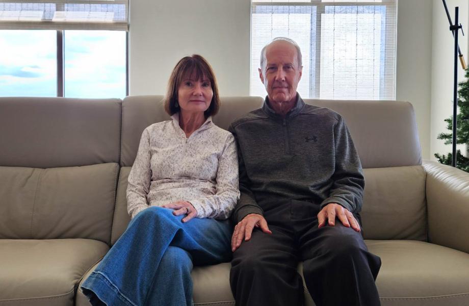 Cathy and her husband sit in their living room.