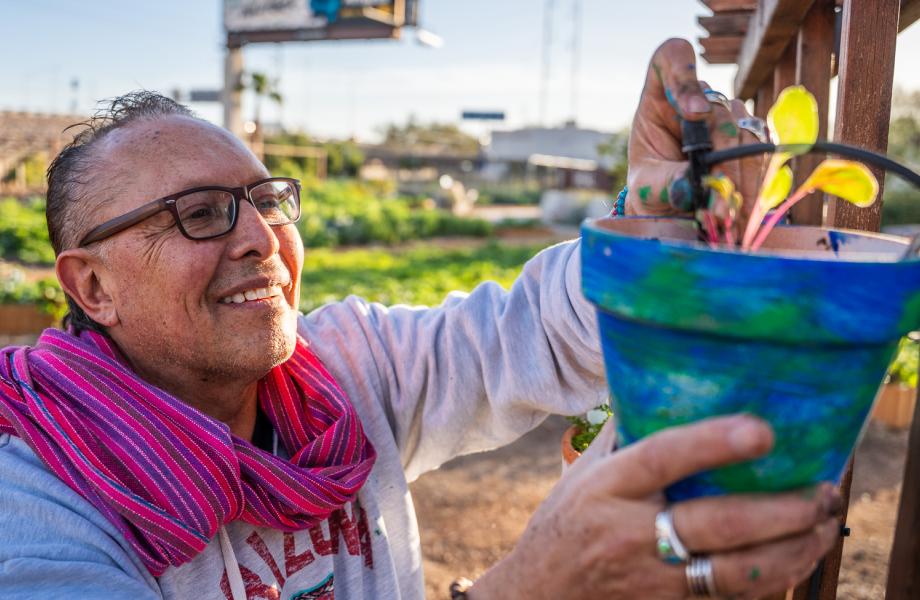 Patricio hangs up the finished potted plant at a trellis in SVdP's Rob and Melani Walton Urban Farm.