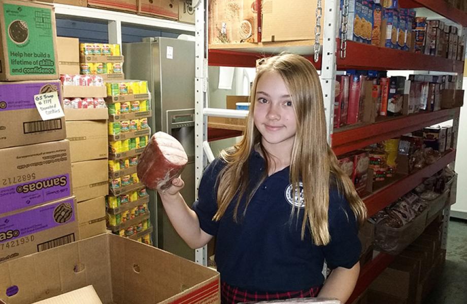 Jacey packs a food box at Our Lady of Mount Carmel food pantry.