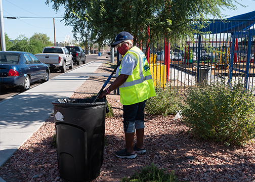 Woman putting trash into a can on the side of the street