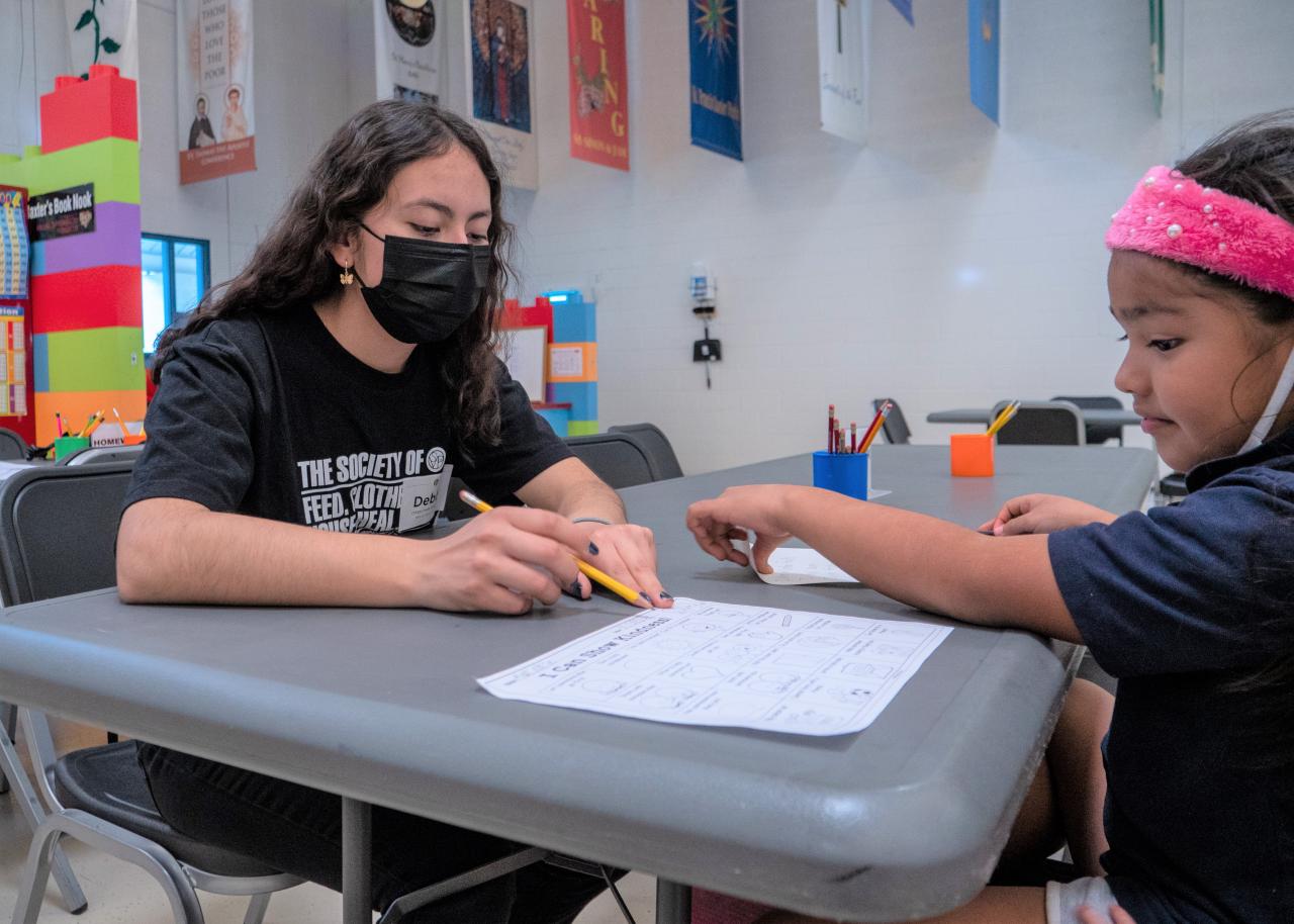 Volunteer working with a young girl on homework