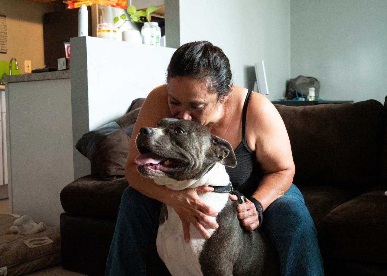 Woman sitting on a couch kissing her dog on the head