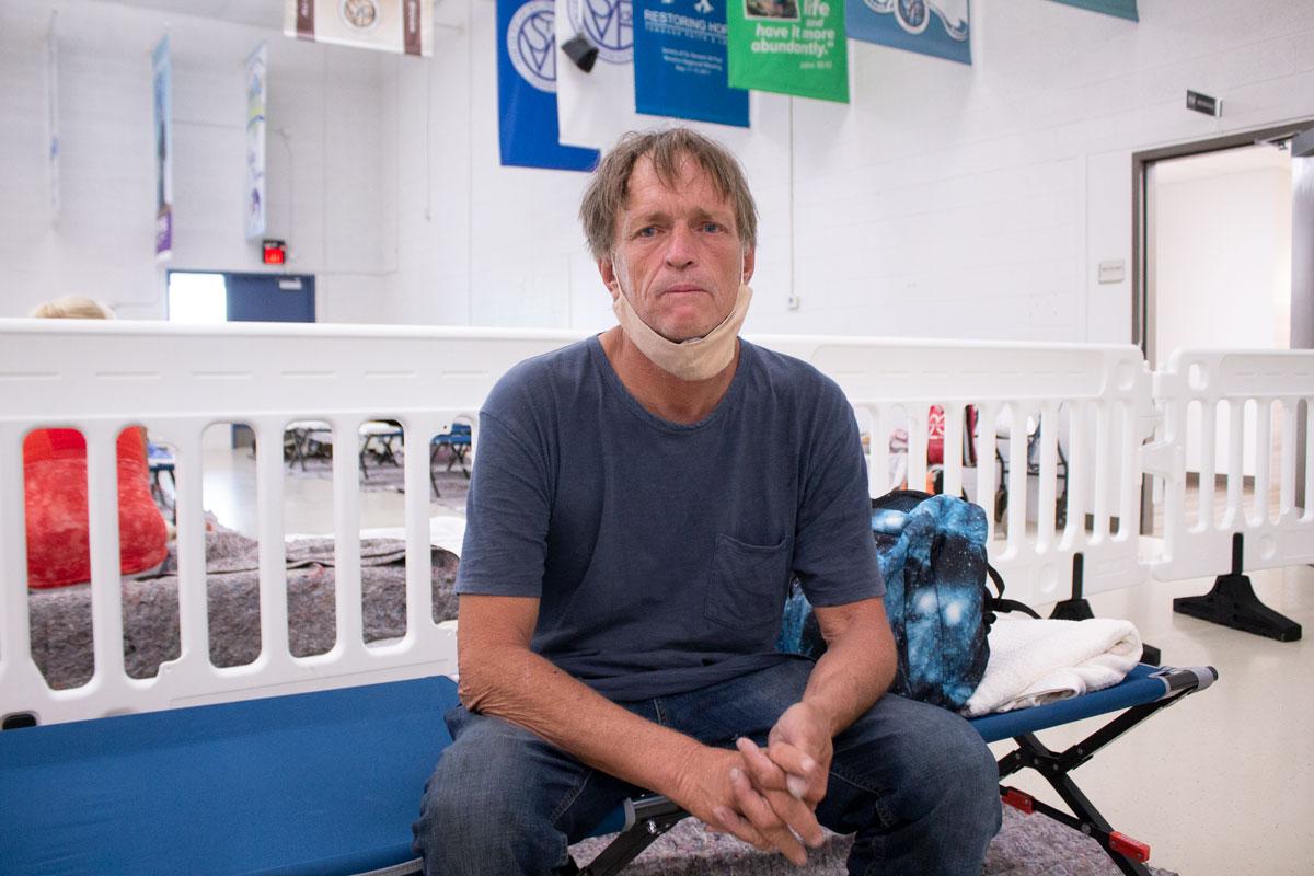 Man sitting on a cot looking into the camera