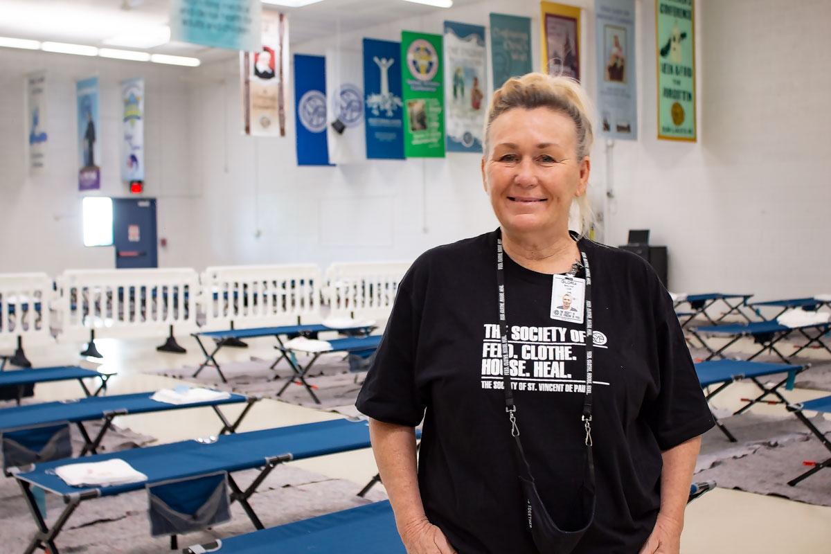 Woman smiling at the camera in a room full of cots