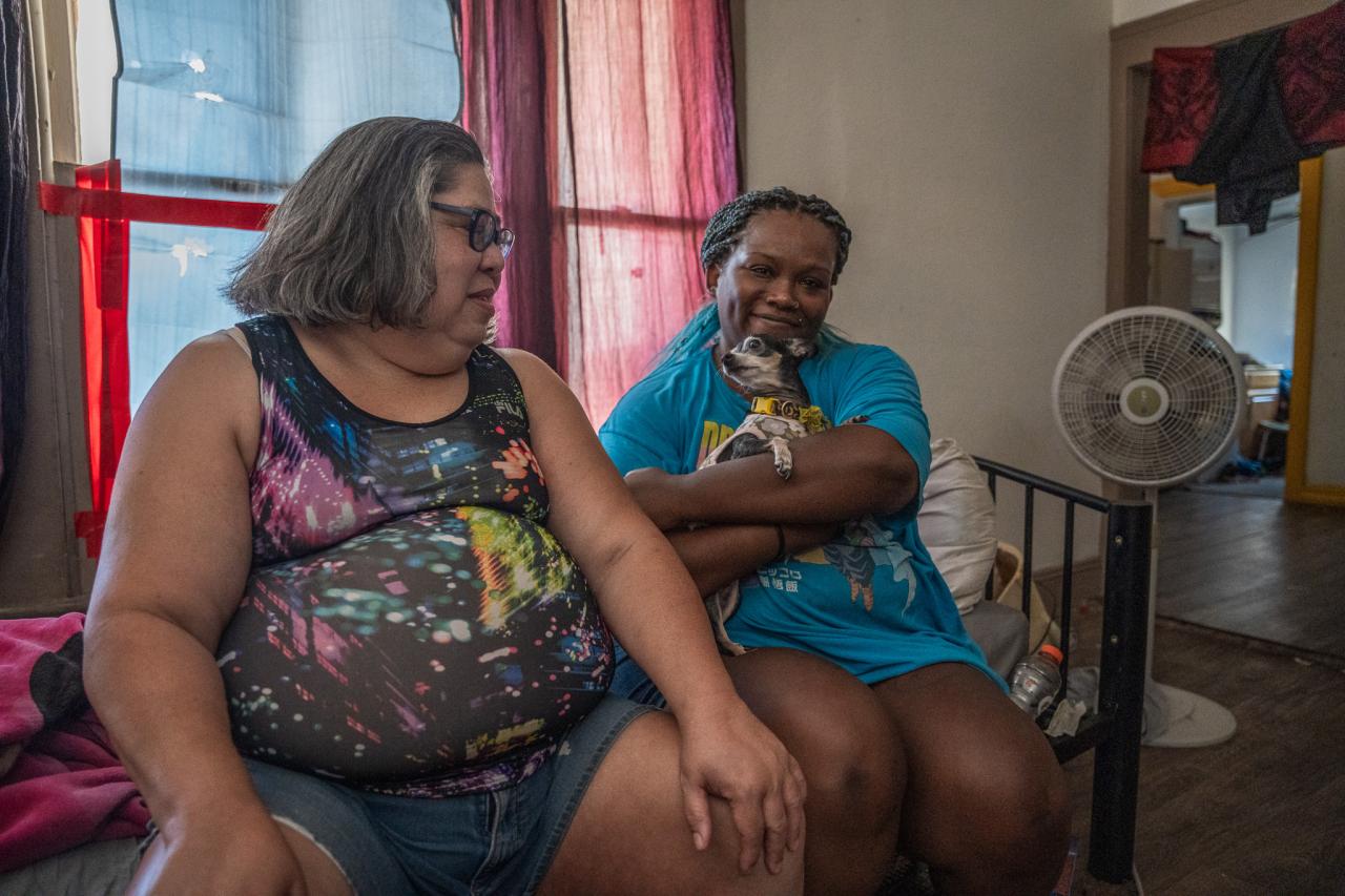 Sandra and Katherine sit in their home with their pet dog.