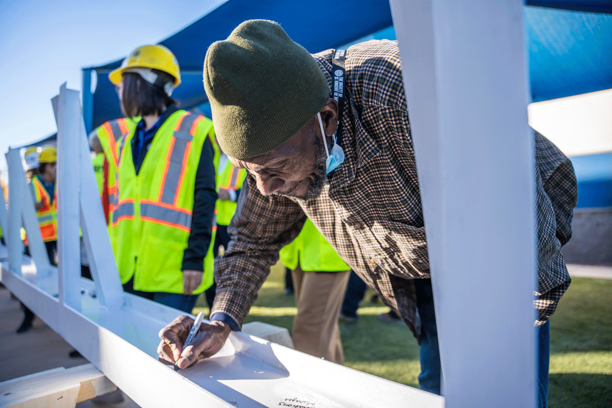 Graduated Oz resident Sylvan McKenzie signs the final steel beam for Oz II