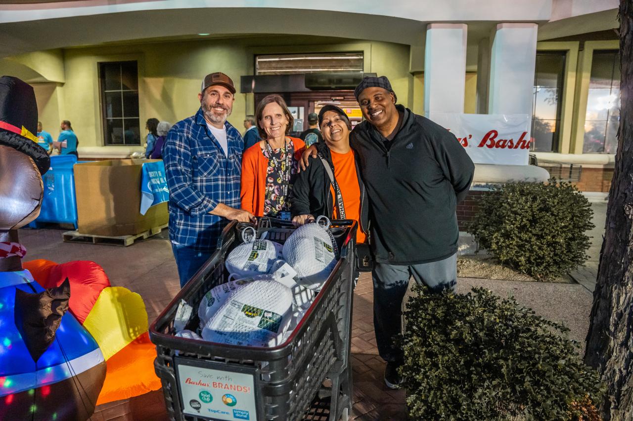 Shannon Clancy, Bruce Cooper, and donors standing with a cart full of frozen turkeys