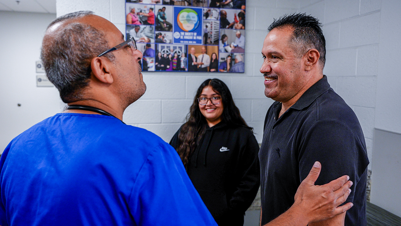 Dr. Anwar greets Luis during a routine visit to SVdP's Virginia G. Piper Medical Clinic. Luis' daughter Anahi looks on with a smile.