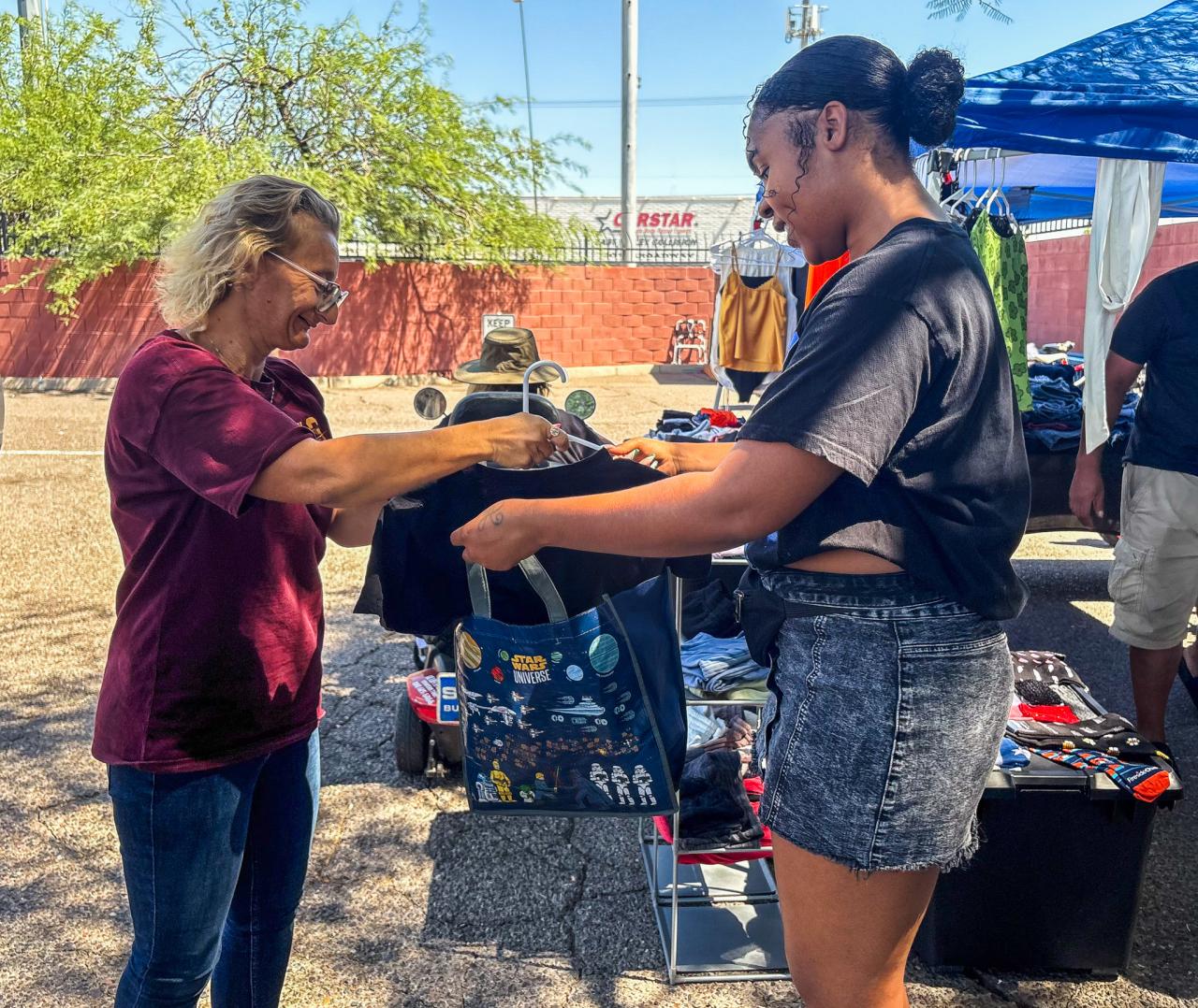McKayla helps a woman bag her clothes at the event.