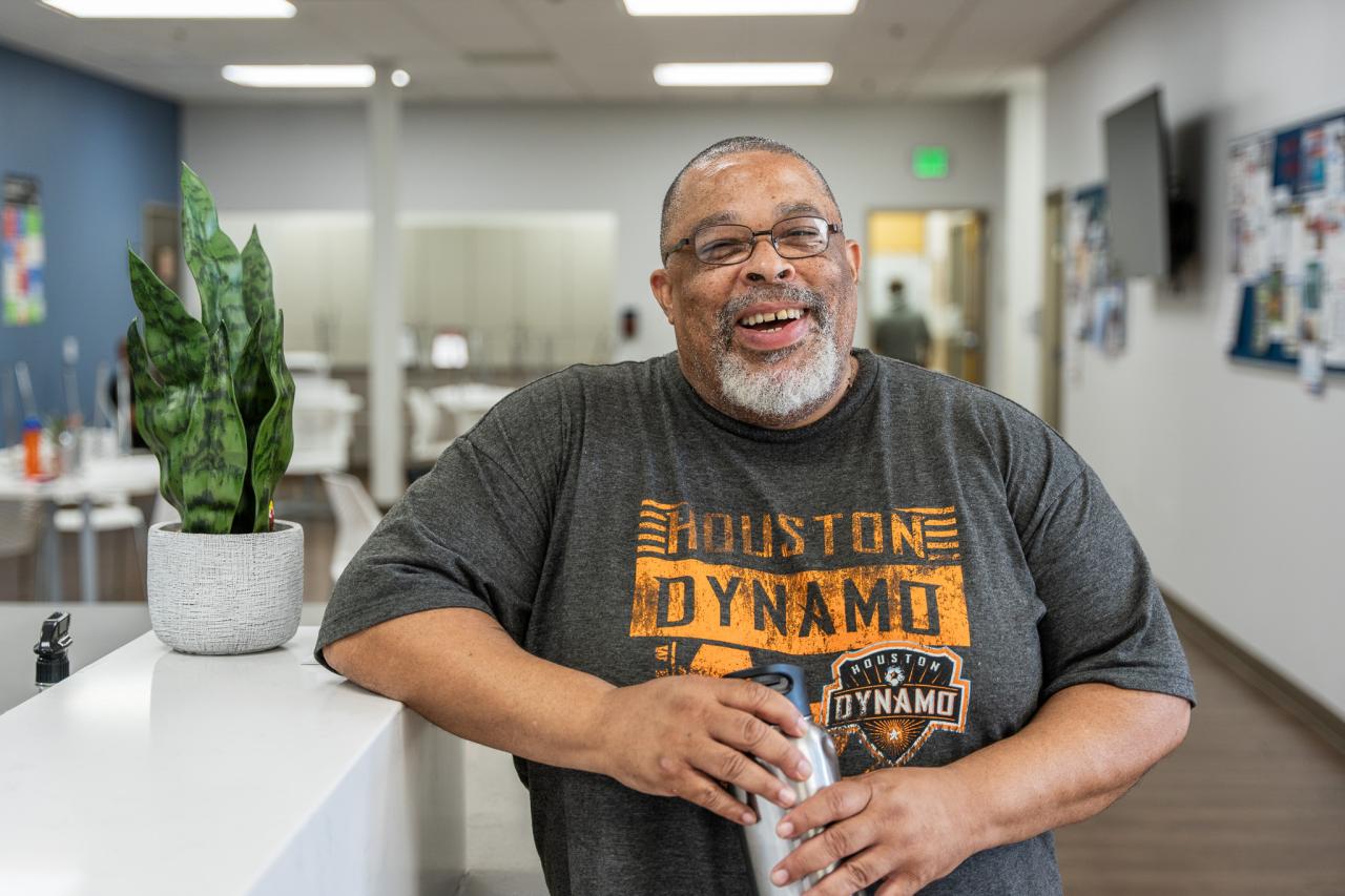 Mark stands by Rosalie's front desk in the common room.