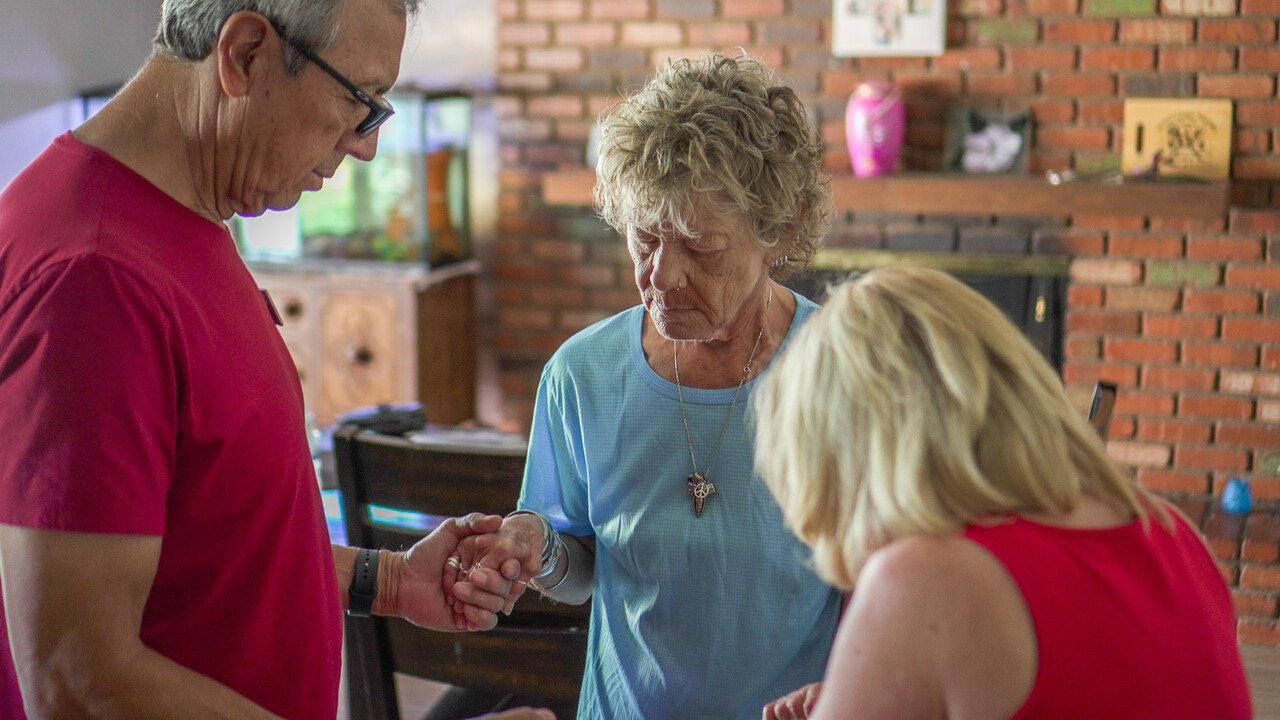 Paula Bishoff prays with the Vincentian volunteers in her home. 
