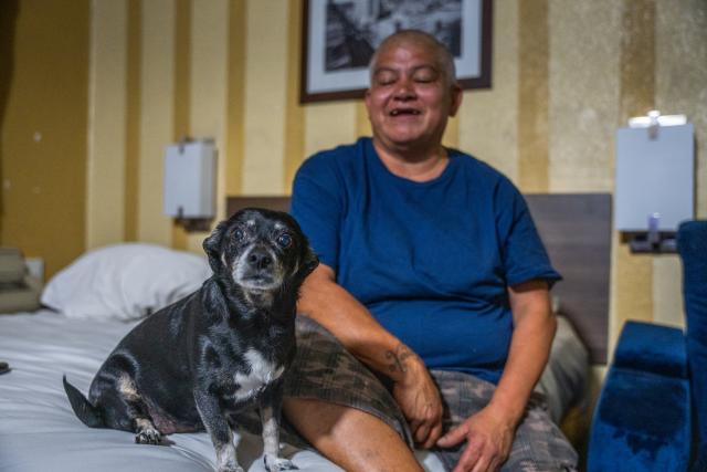 Woman sitting on a bed in an SVdP shelter with her dog sitting next to her